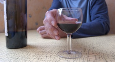 Hånd, der rækker ud efter glas med rødvin